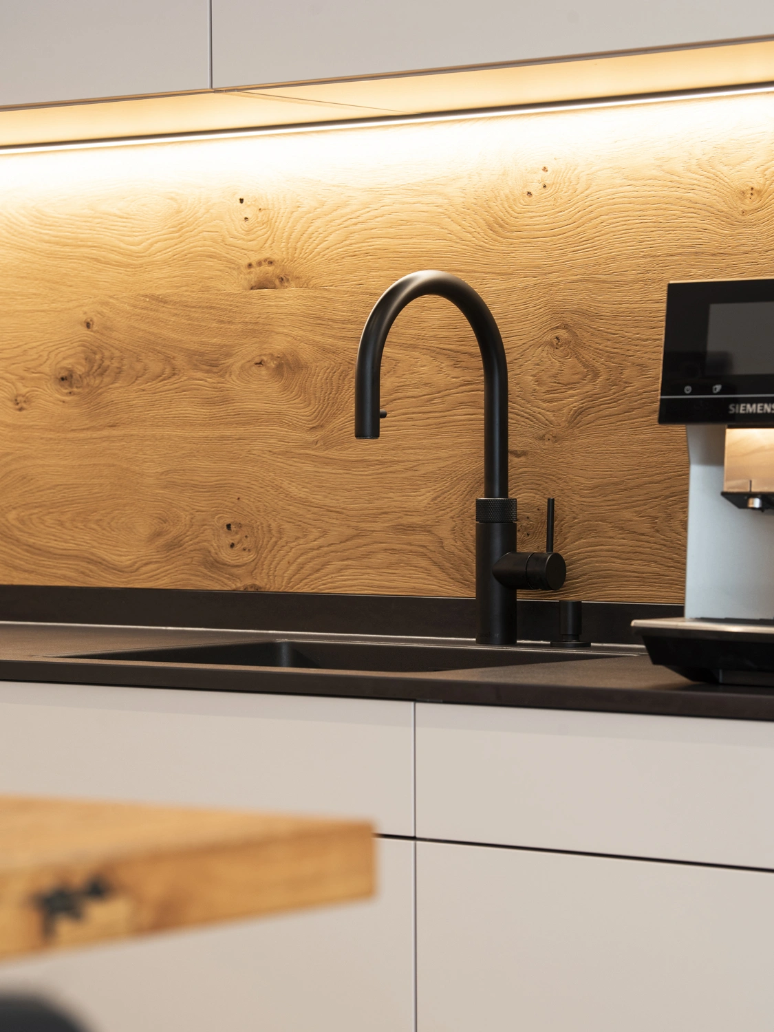 Detail schwarze Armatur vor Holzrückwand