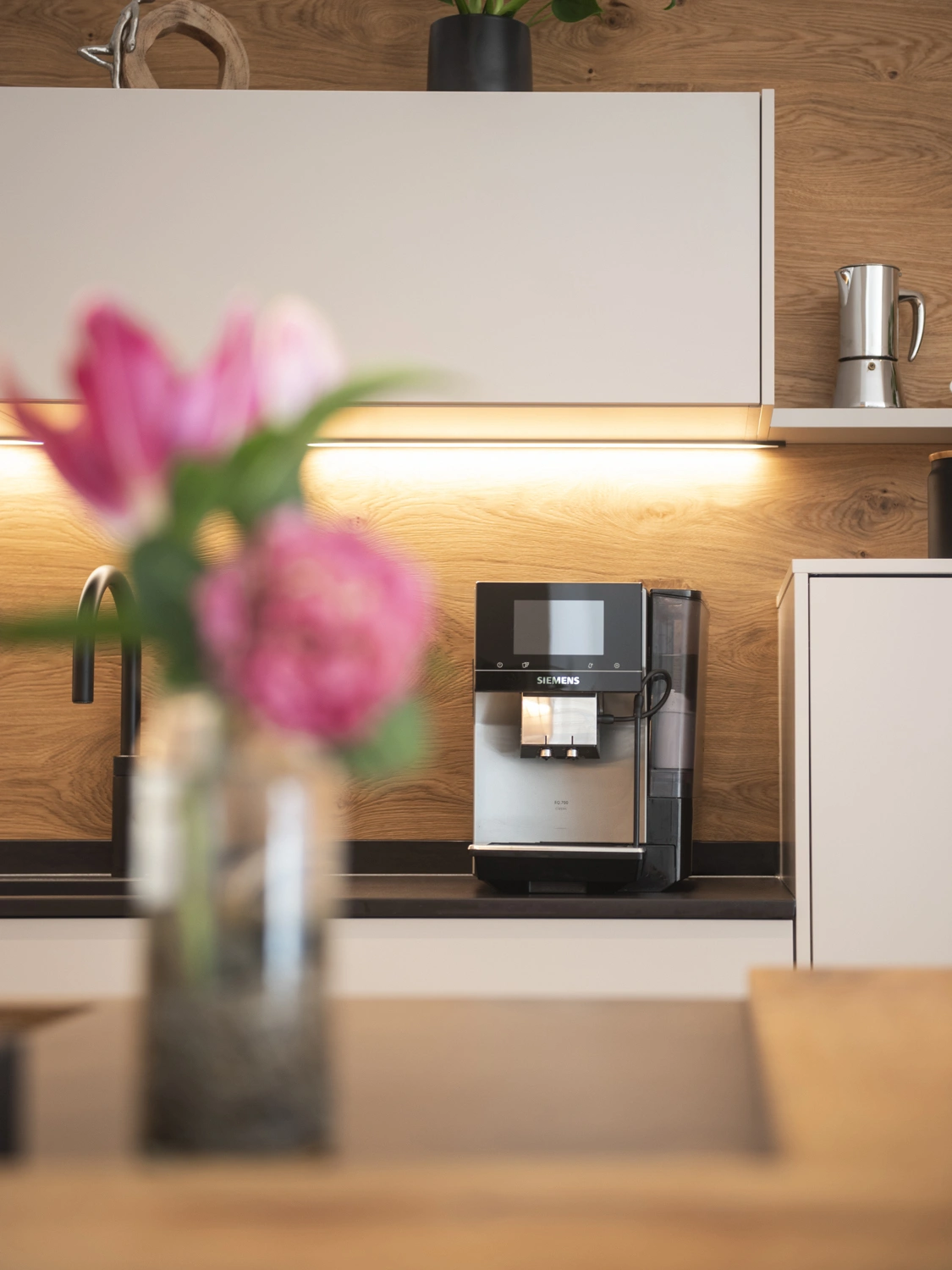 Detailansicht Kaffeemaschine mit Blumen im Vordergrund